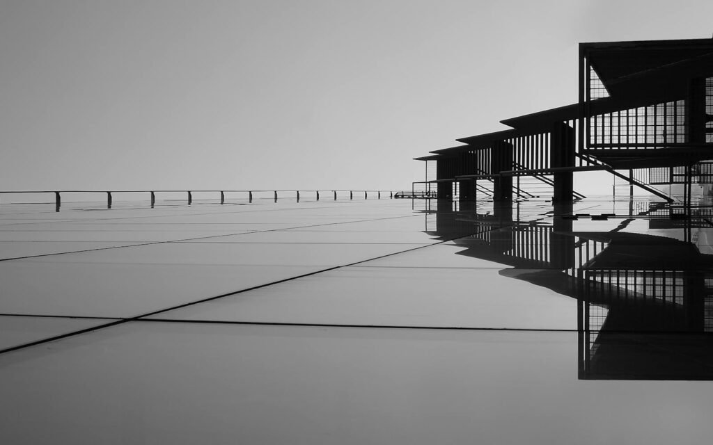 Arquitecto Deluca Valencia A striking minimalist black and white image featuring architectural reflections on glass surfaces.